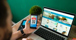 How to Start an Ecommerce Business Without Capital young-man-using-discount-coupon-his-smartphone-some-online-shopping-laptop-scaled