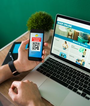 How to Start an Ecommerce Business Without Capital young-man-using-discount-coupon-his-smartphone-some-online-shopping-laptop-scaled